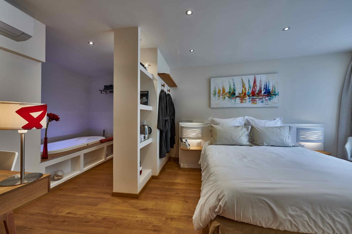 Um quarto moderno com uma cama grande, uma escrivaninha com luminária, uma estante de livros e um quadro na parede.