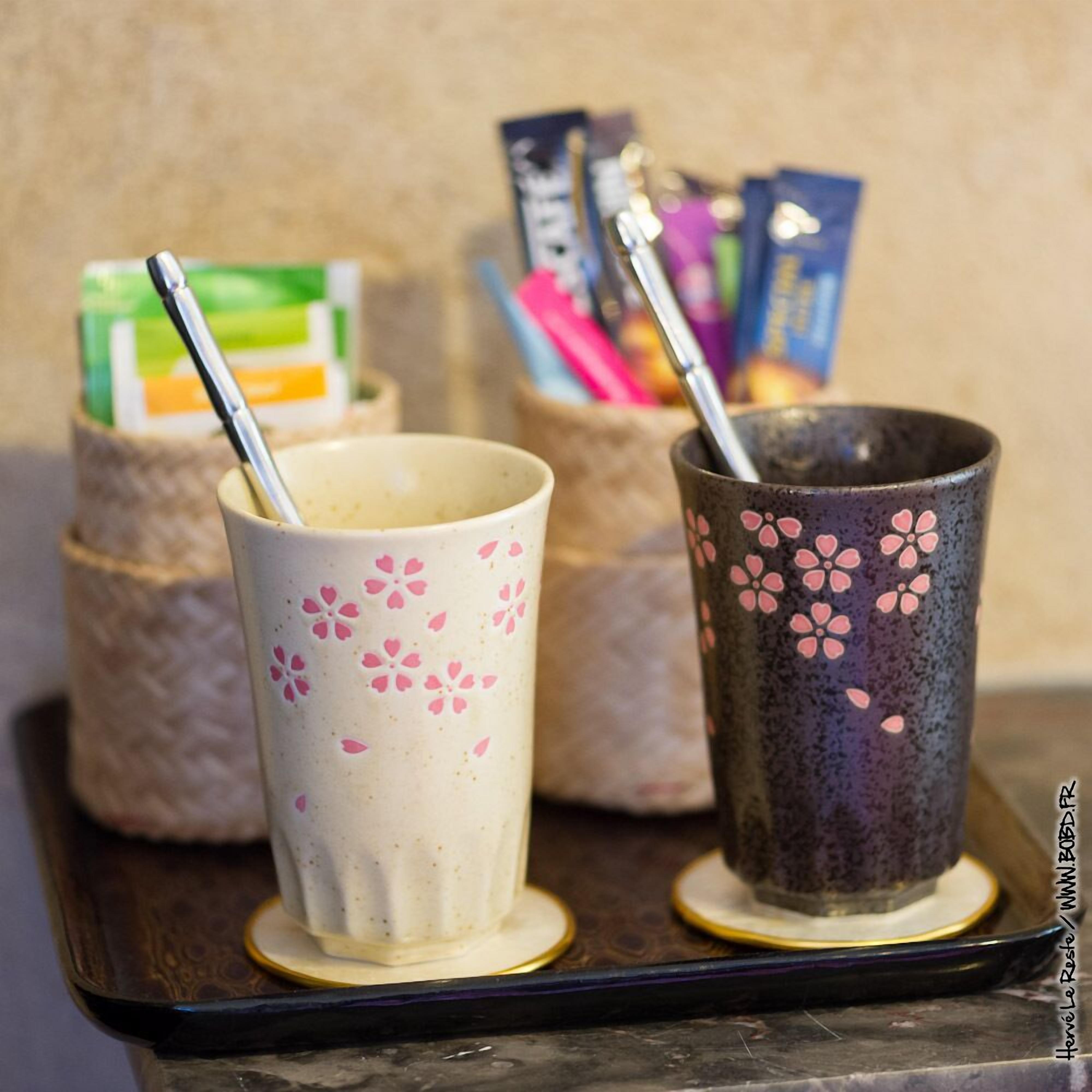 Two ceramic cups with floral designs on a tray.
