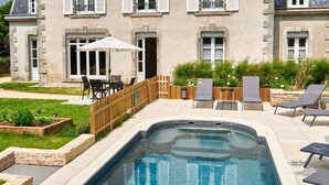 Ein großes Haus mit Swimmingpool, Gartenmöbeln und einem Garten.
