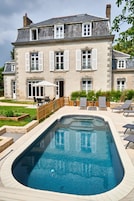 A large house with a swimming pool, outdoor furniture, and a garden.