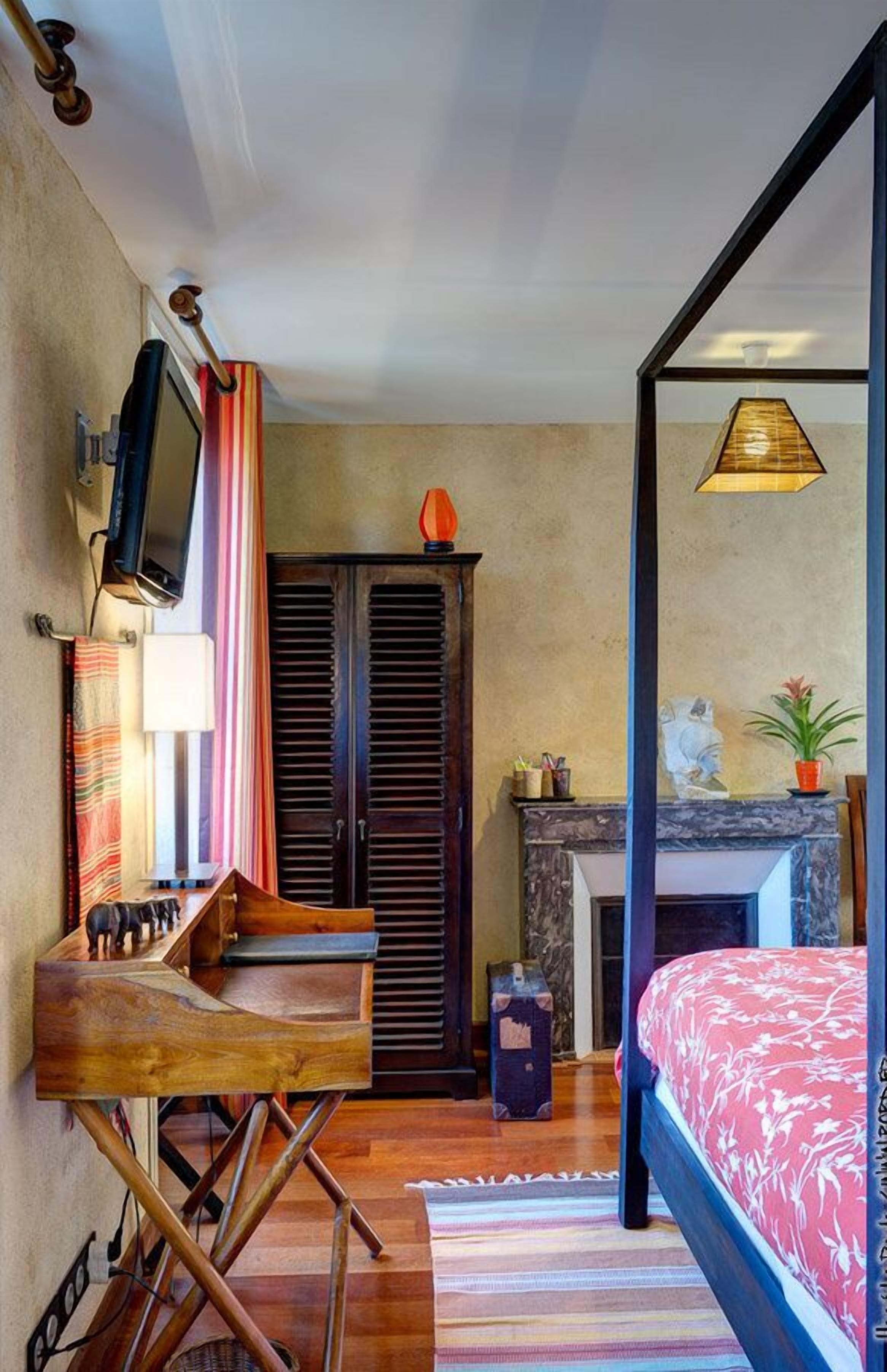 A bedroom with a bed, a television, a wardrobe, a fireplace, and a window with curtains.