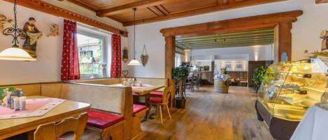 A cozy restaurant with wooden furniture, a central serving counter, and a view of the kitchen in the background.