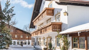 Un bâtiment alpin traditionnel, avec des balcons en bois, une enseigne indiquant une banque, et de la neige au sol.