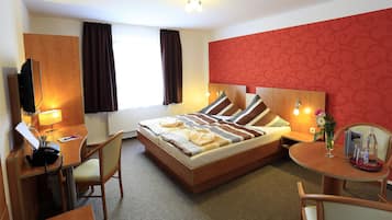 A hotel room with a bed, desk, chair, and a small table with a tray.