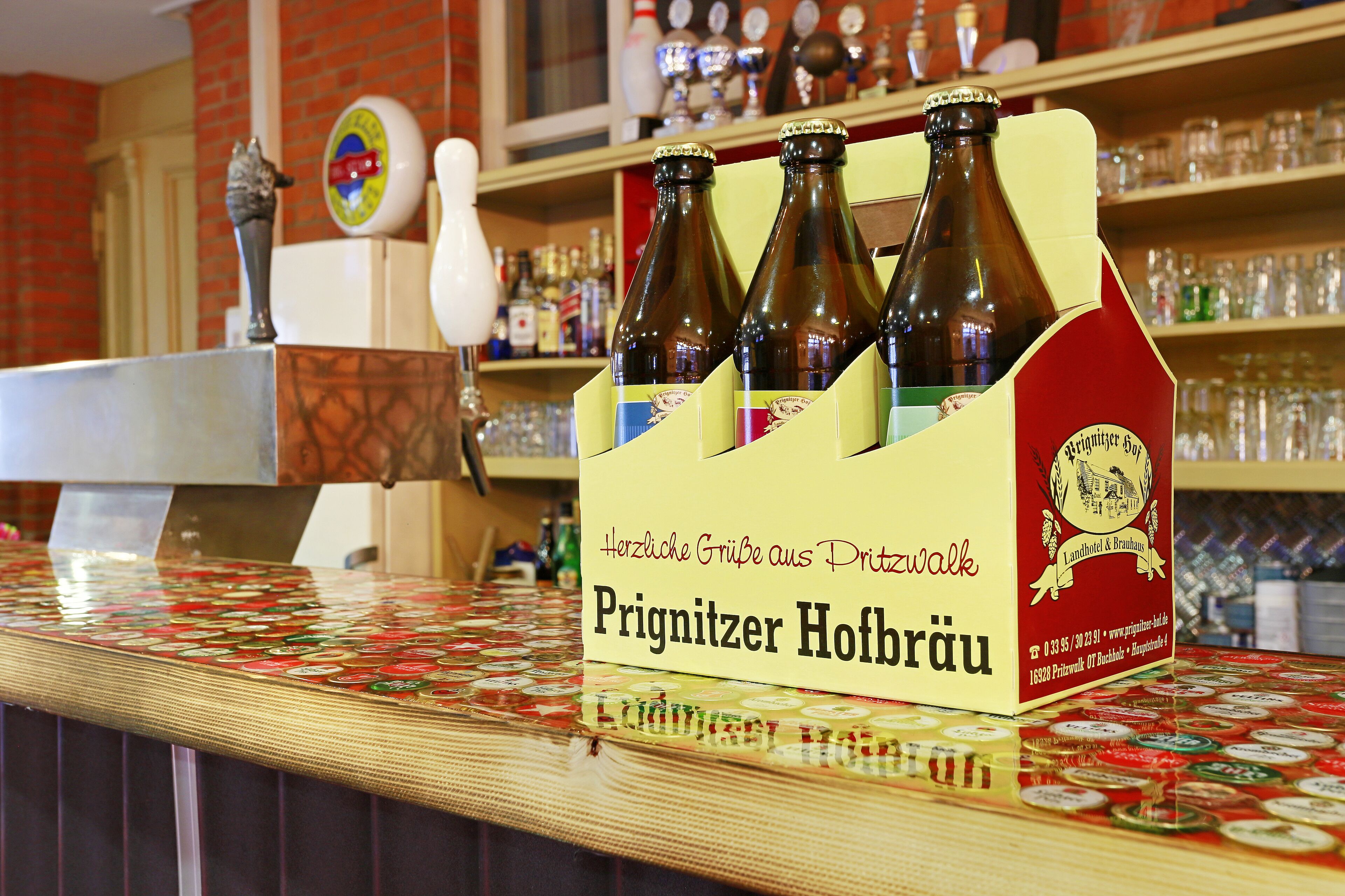 A bar counter with a Prignitzer Hofbräu beer tap and a decorative beer bottle holder.