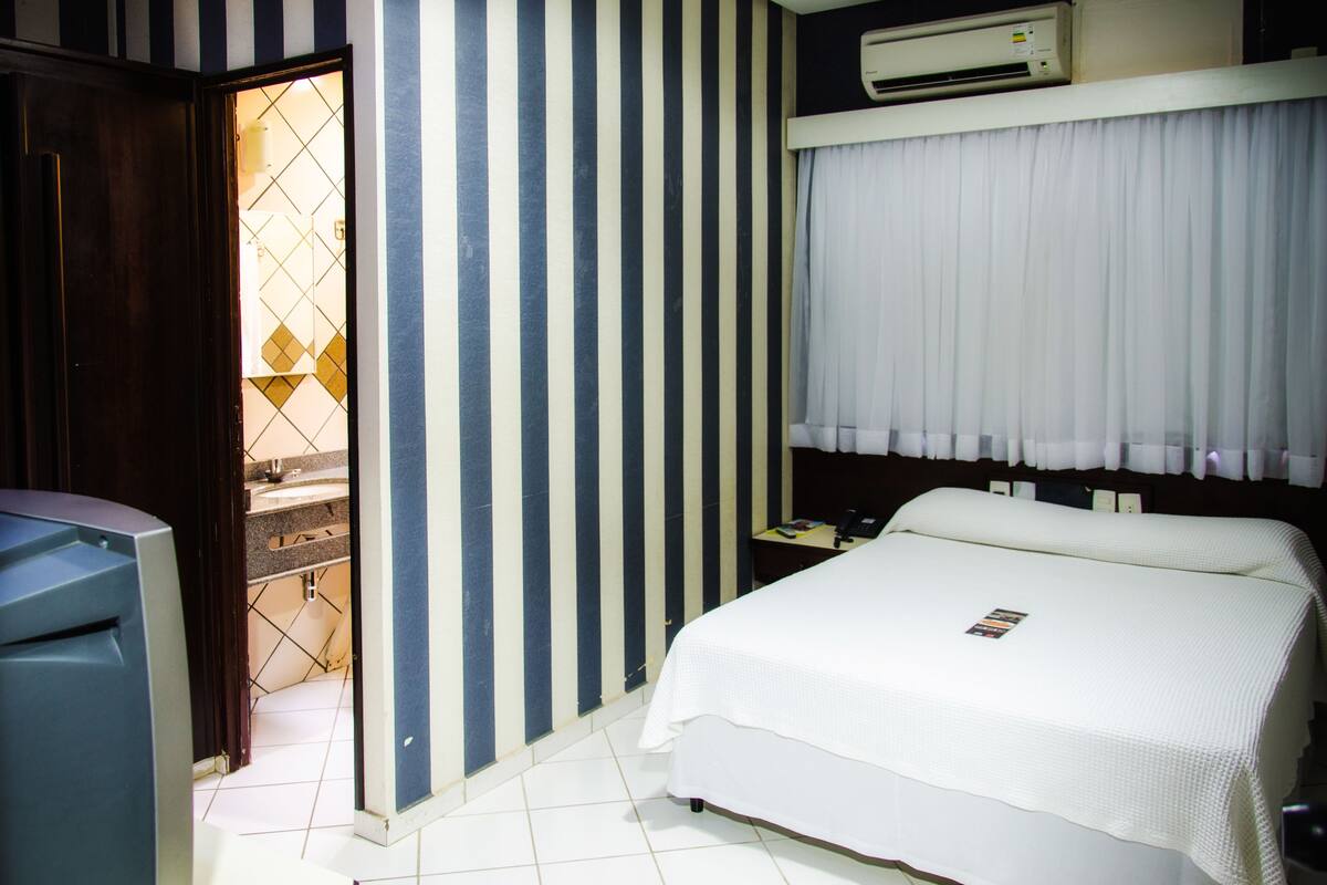 Une chambre d’hôtel avec un lit, un bureau et une armoire.