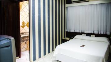 A hotel room with a bed, a desk, and a wardrobe.