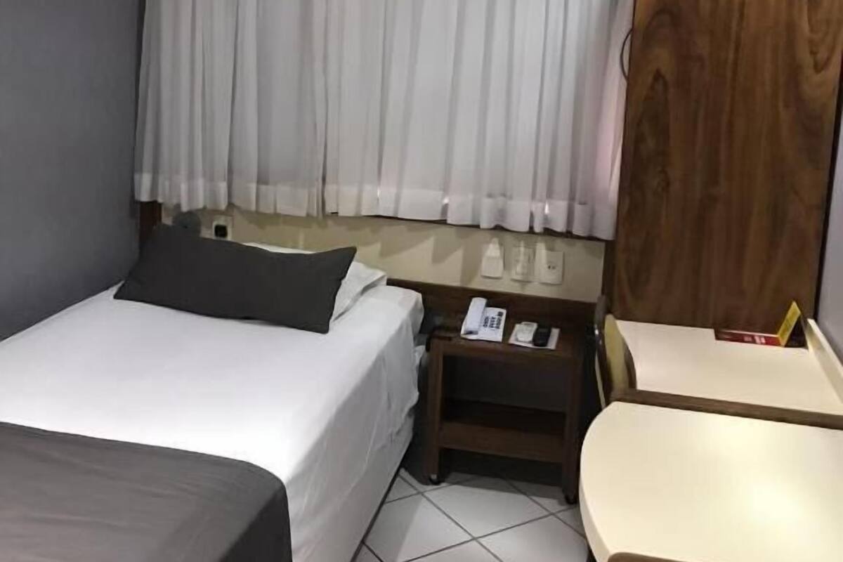 Une chambre d’hôtel avec un lit, une table de chevet et un petit bureau.