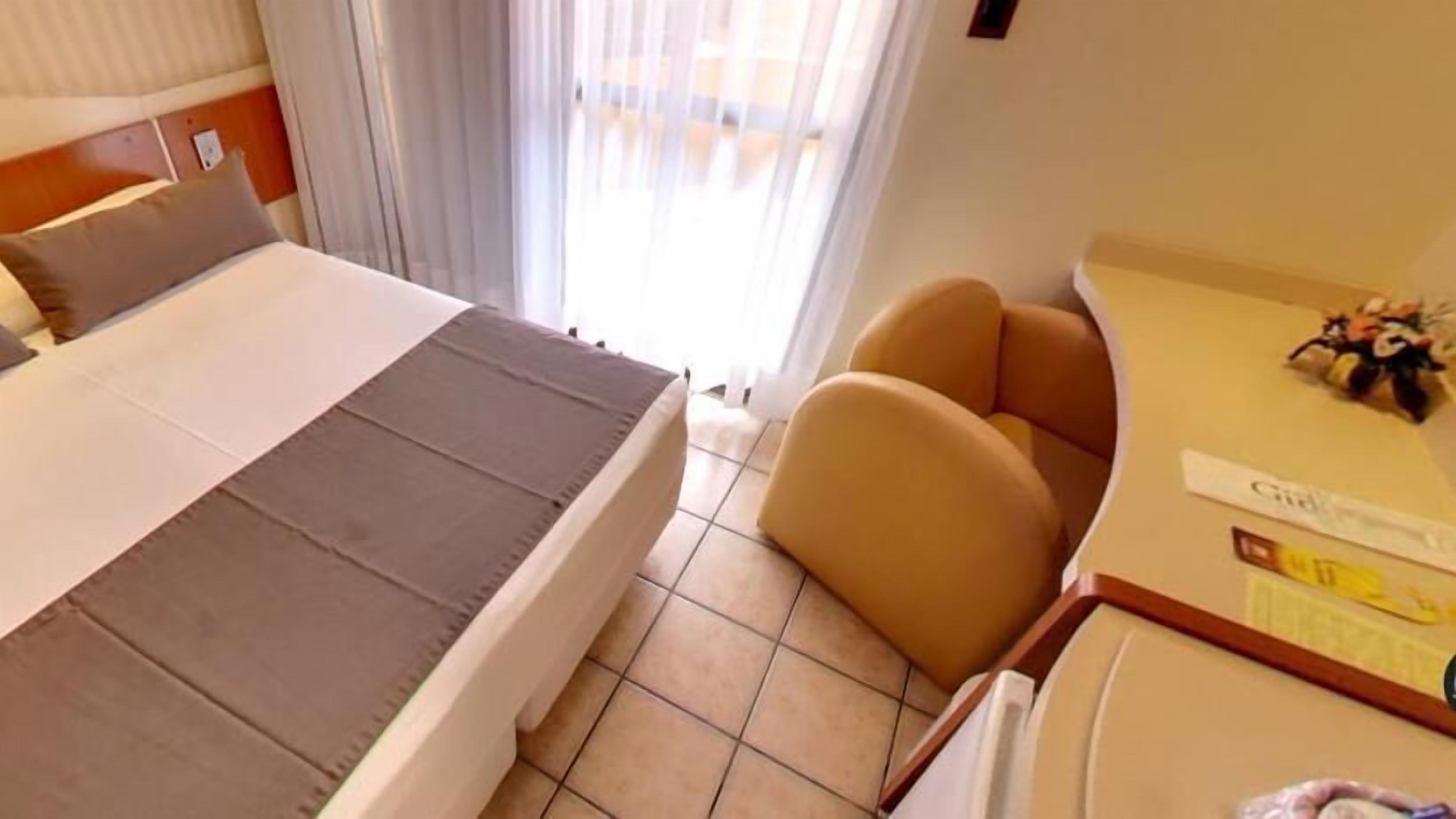A hotel room with a bed, a desk, and a chair.