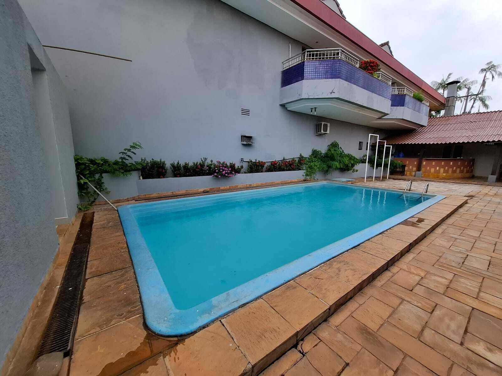 A rectangular swimming pool with a tiled edge, surrounded by a brick patio.