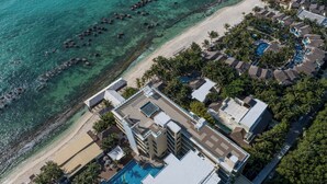 Vista aérea de un resort con playa, aguas cristalinas y zona de piscina.