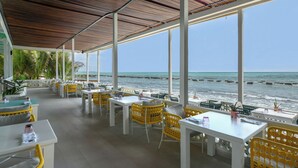 Un restaurant en bord de mer avec une terrasse, de grandes fenêtres et une vue sur l’océan.