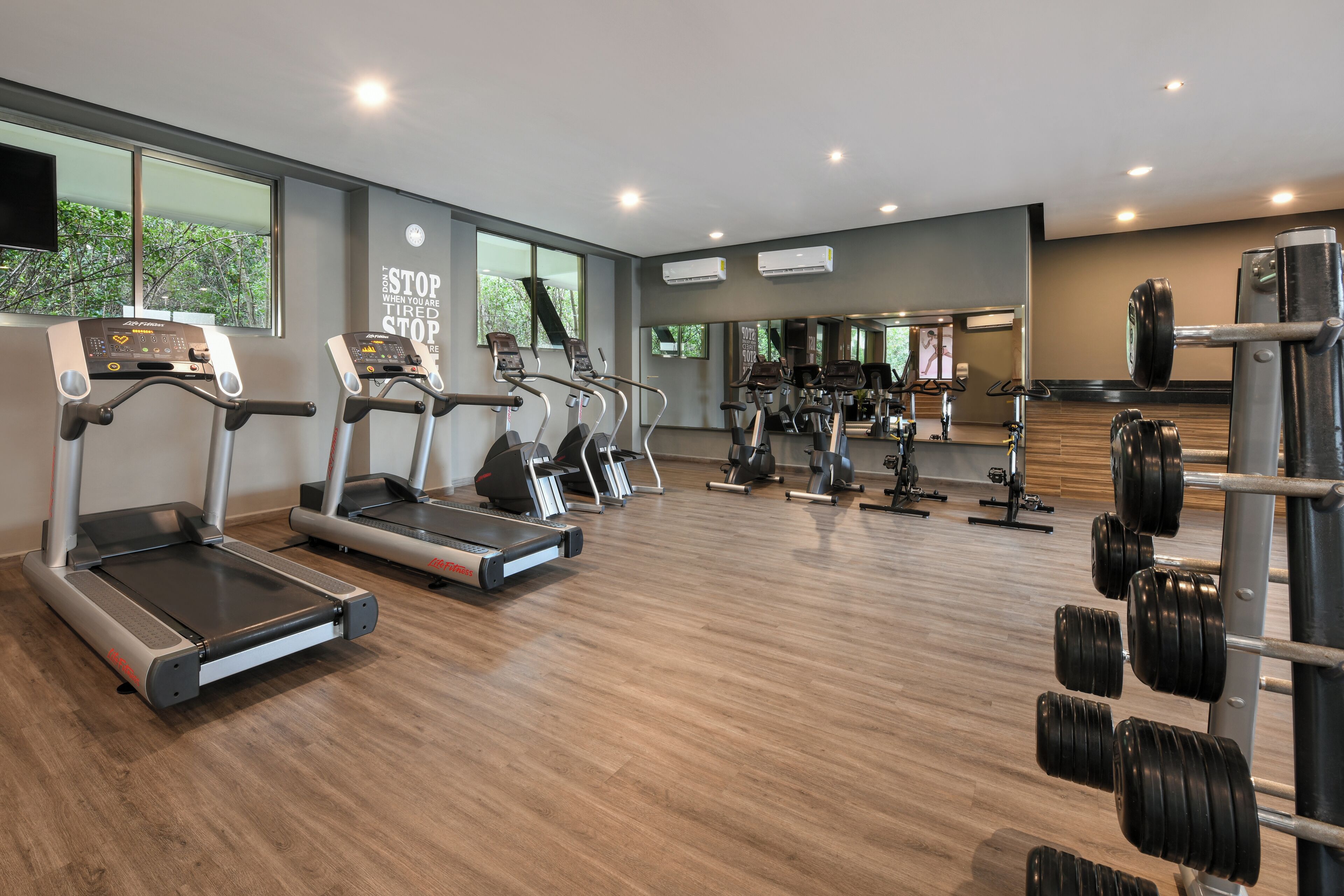 Ein modernes Fitnessstudio mit Laufbändern, Kraftgeräten und einer Spiegelwand.