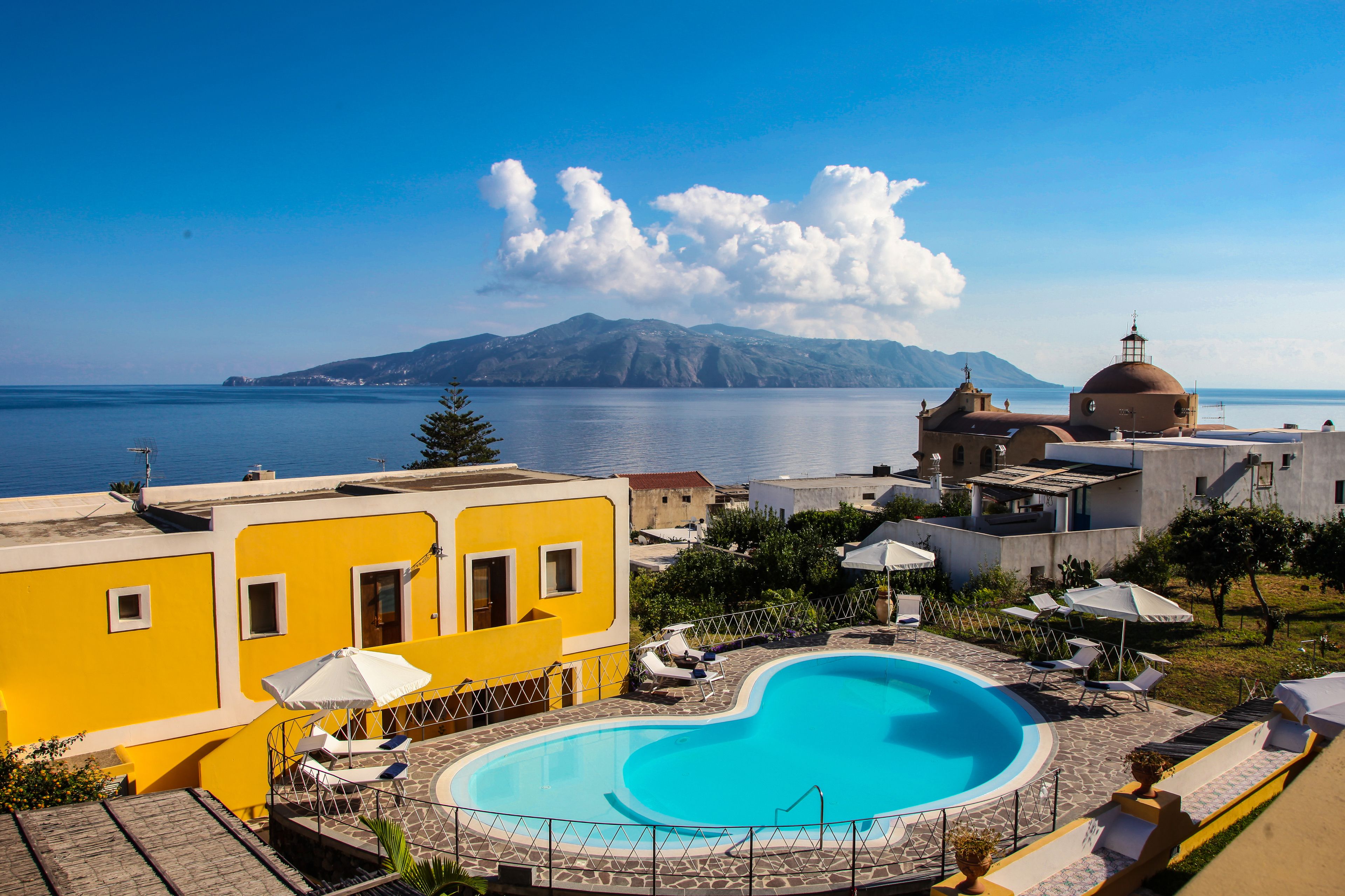 A pool area with a view of the sea and a mountain in the background.