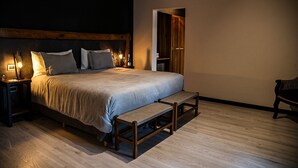 A bedroom with a large bed, wooden headboard, bedside tables with lamps, a bench, and a wardrobe. - Algodon Wine Estates and Champions Club (San Rafael)