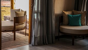 A cozy seating area with a cushioned bench and a sofa, both with pillows. A wooden floor and a window with curtains are visible. - Algodon Wine Estates and Champions Club (San Rafael)