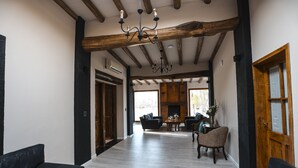 A spacious room with a high ceiling, wooden beams, and a chandelier. There is a fireplace, a dining table with chairs, and a seating area with sofas and a chair. - Algodon Wine Estates and Champions Club (San Rafael)