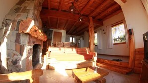 Un interior rústico con chimenea de piedra, vigas de madera y una zona de estar acogedora.