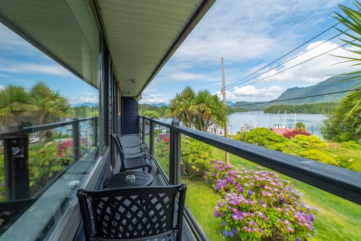 Ein Balkon mit Blick auf einen See und Berge, ausgestattet mit Tisch und Stühlen.