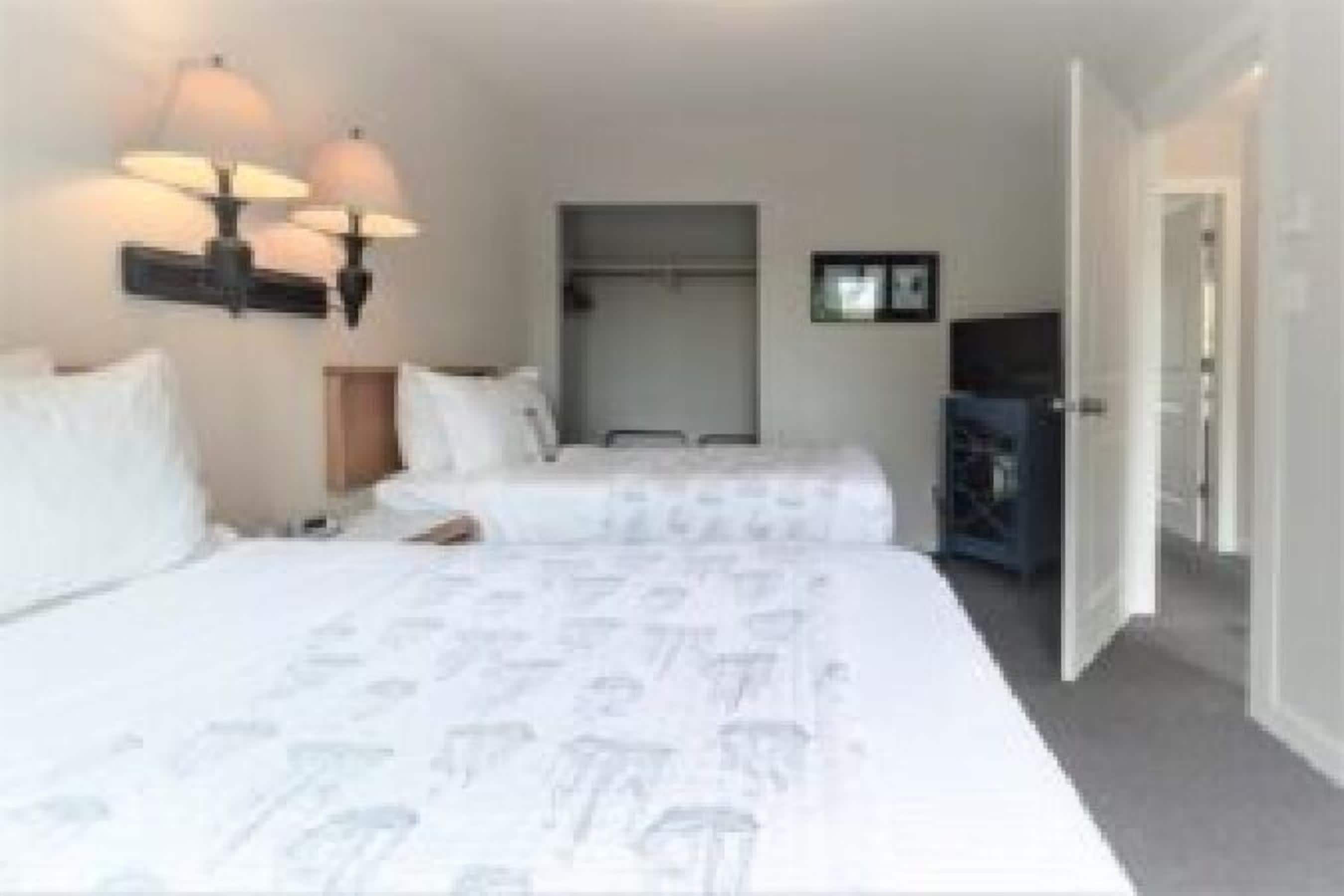 Una habitación de hotel con dos camas, un armario, un televisor y una lámpara fijada a la pared.