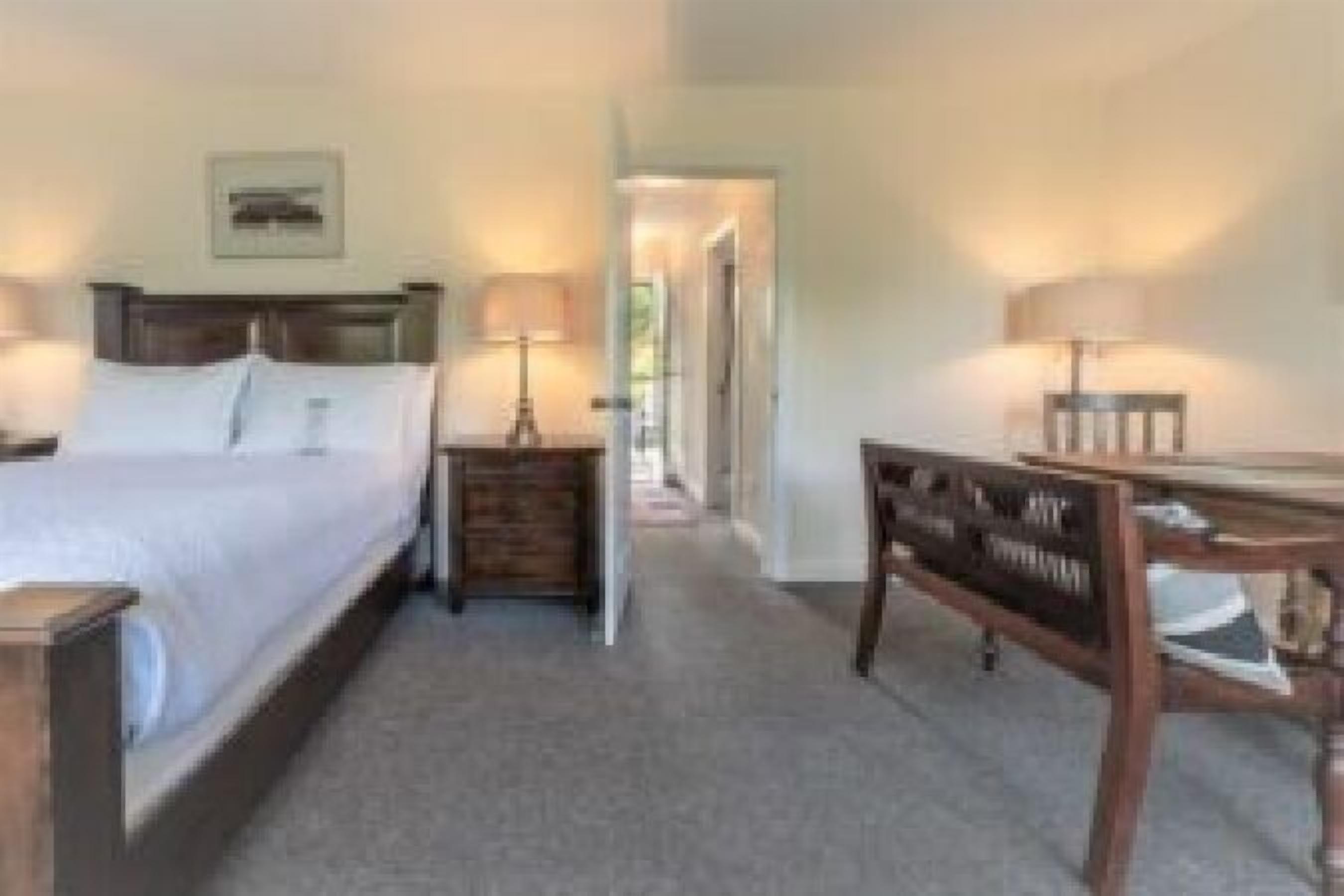 A bedroom with a bed, bedside tables, a desk, and a chair.