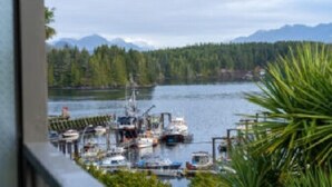 A marina with boats docked, surrounded by forest and mountains. - Tofino Motel Harborview (Tofino)