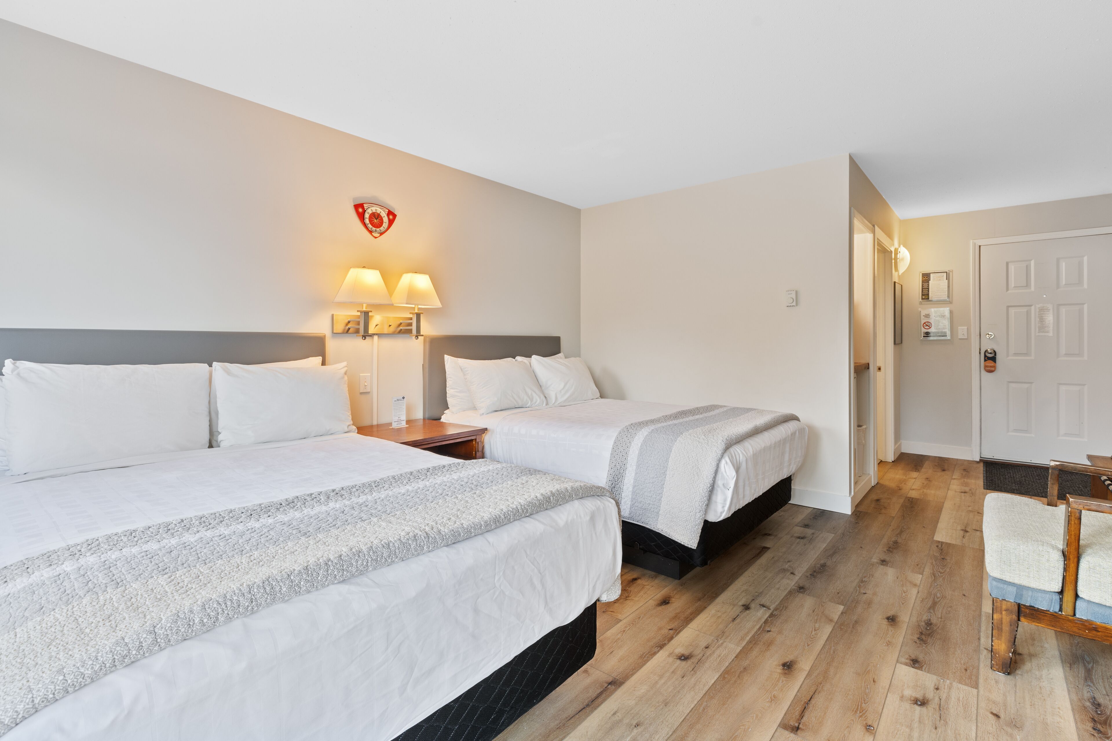 Habitación de hotel con dos camas, piso de madera y una puerta.