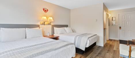 Habitación de hotel con dos camas, piso de madera y una puerta.