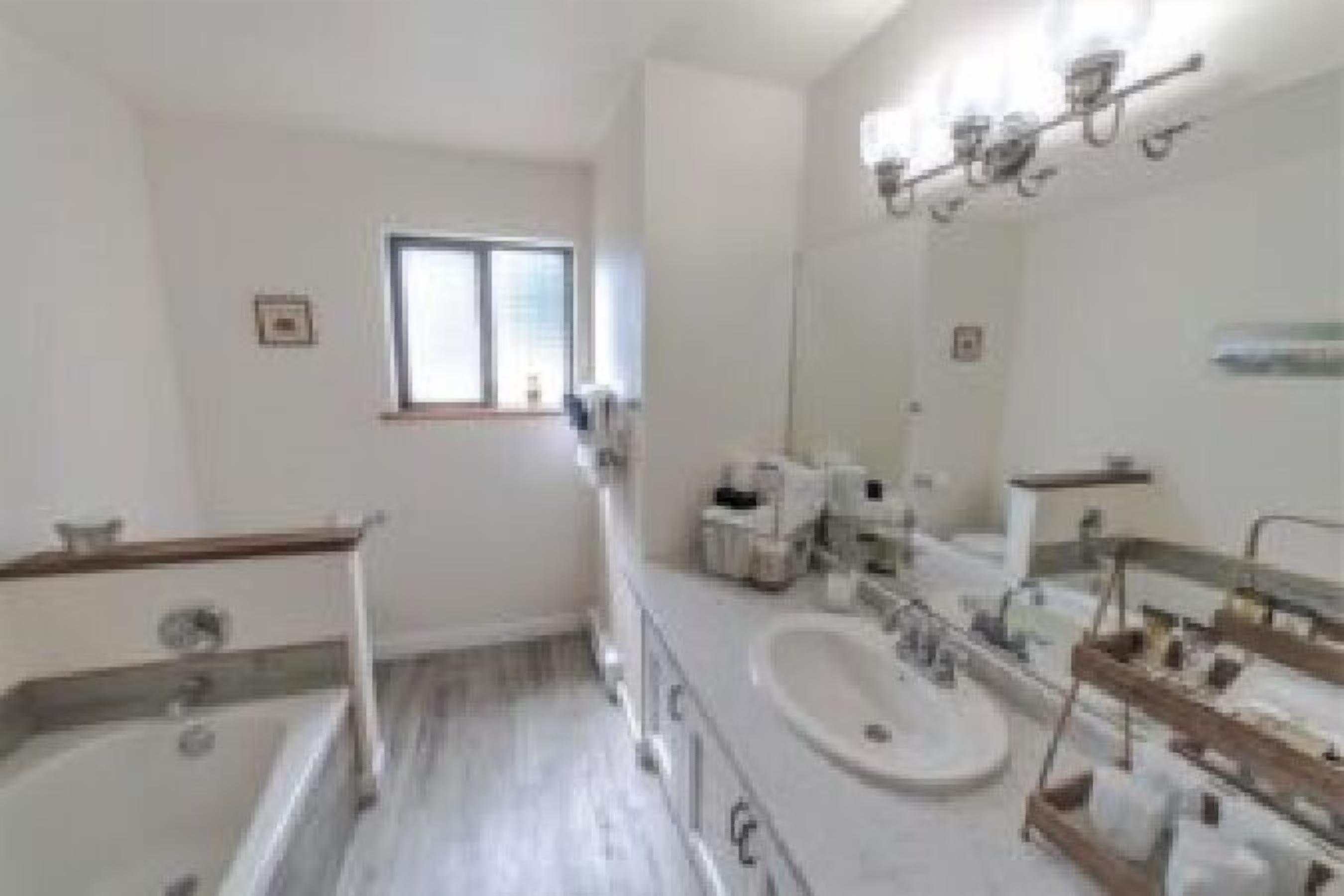 A modern bathroom with a large mirror, a bathtub, and a double sink.