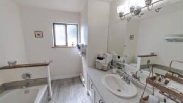A modern bathroom with a large mirror, a bathtub, and a double sink.