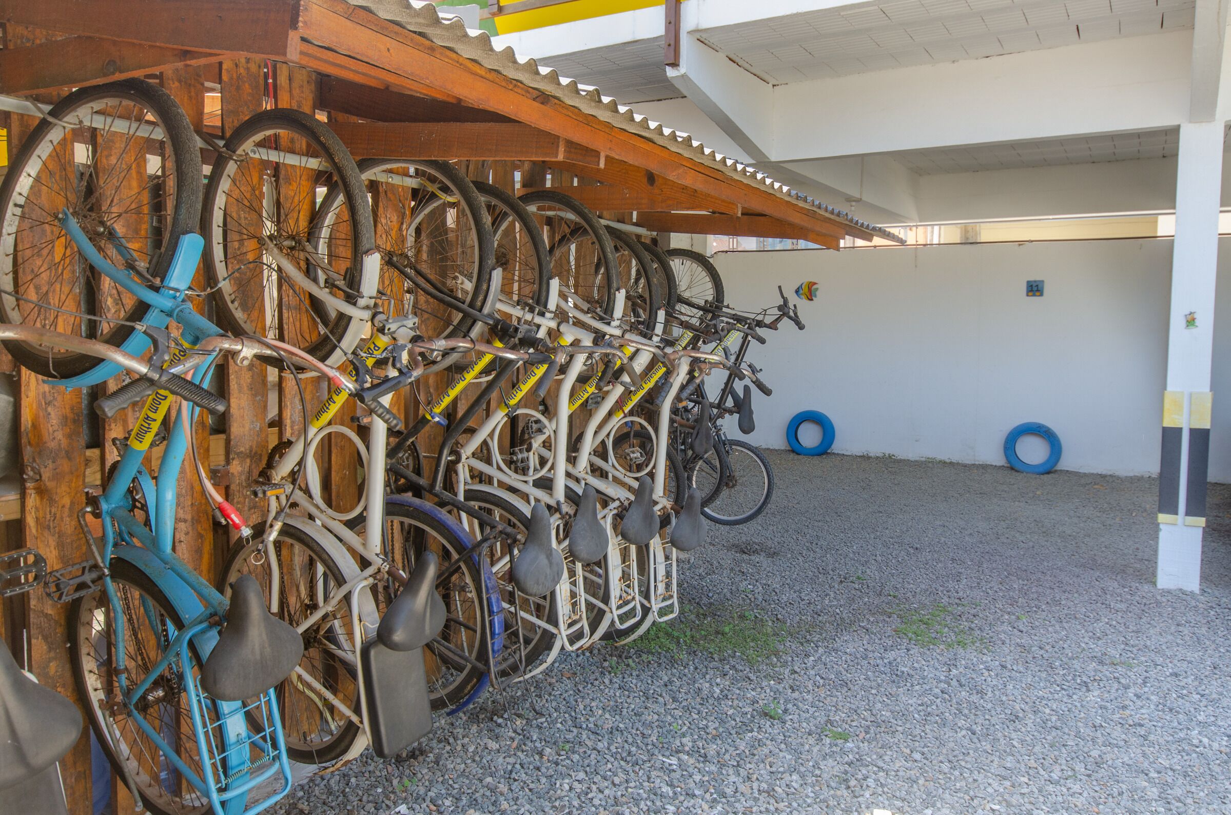 Área de estacionamento coberta para bicicletas, com várias bicicletas presas a um suporte.