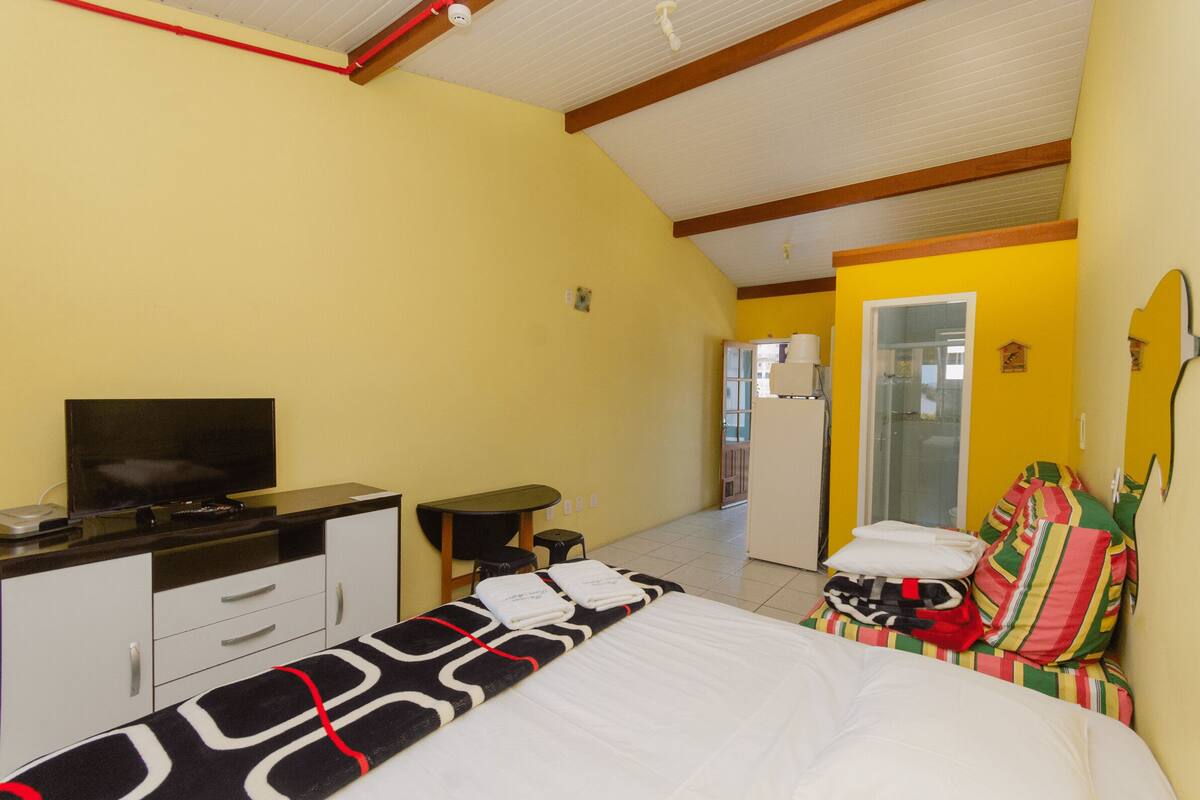 Une chambre d’hôtel avec un lit, une télévision, un bureau et une salle de bain visible à travers une porte ouverte.