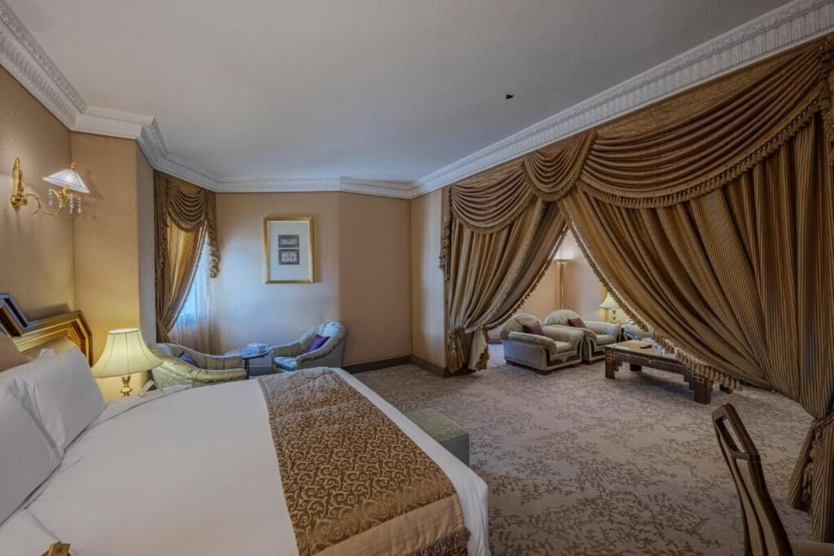 Une chambre d’hôtel spacieuse, dotée d’un grand lit, de deux fauteuils, d’un canapé et d’une petite table.