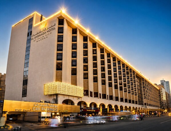 A hotel with a prominent sign, multiple floors, and a car parking area. - Al Shohada by Palm Rich Makkah (Makkah)