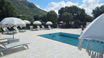 En säsongsöppen utomhuspool, parasoller och solstolar
