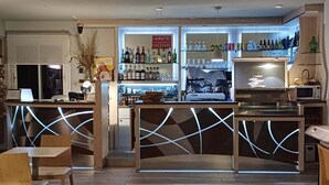 Zona de bar con mostrador, asientos y una variedad de botellas y vasos.