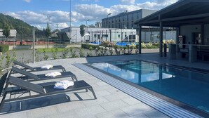 A swimming pool with lounge chairs and a covered seating area. - Hotel Davídek (Trutnov)