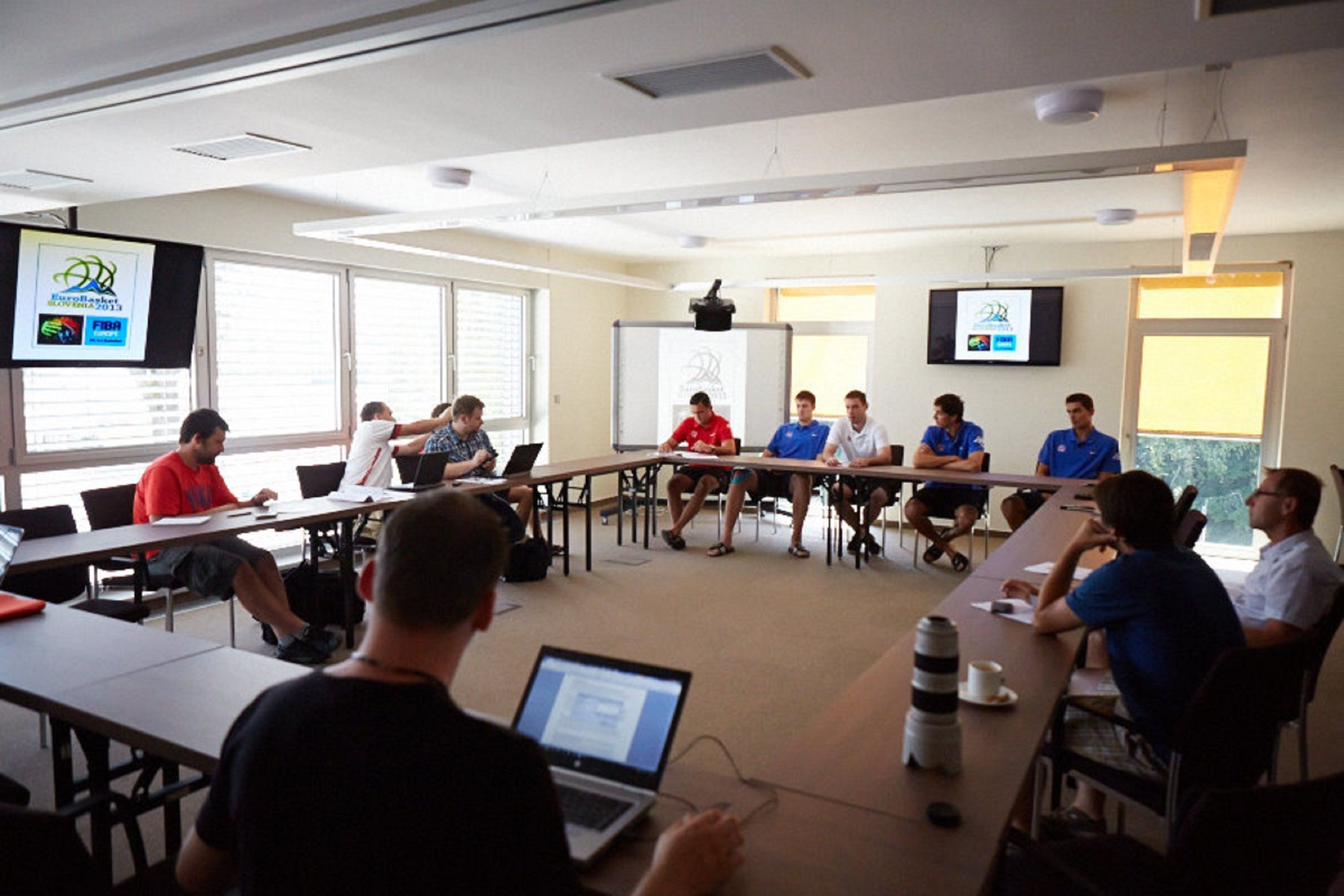 Ein Konferenzraum mit einem langen Tisch, Stühlen und Laptops.