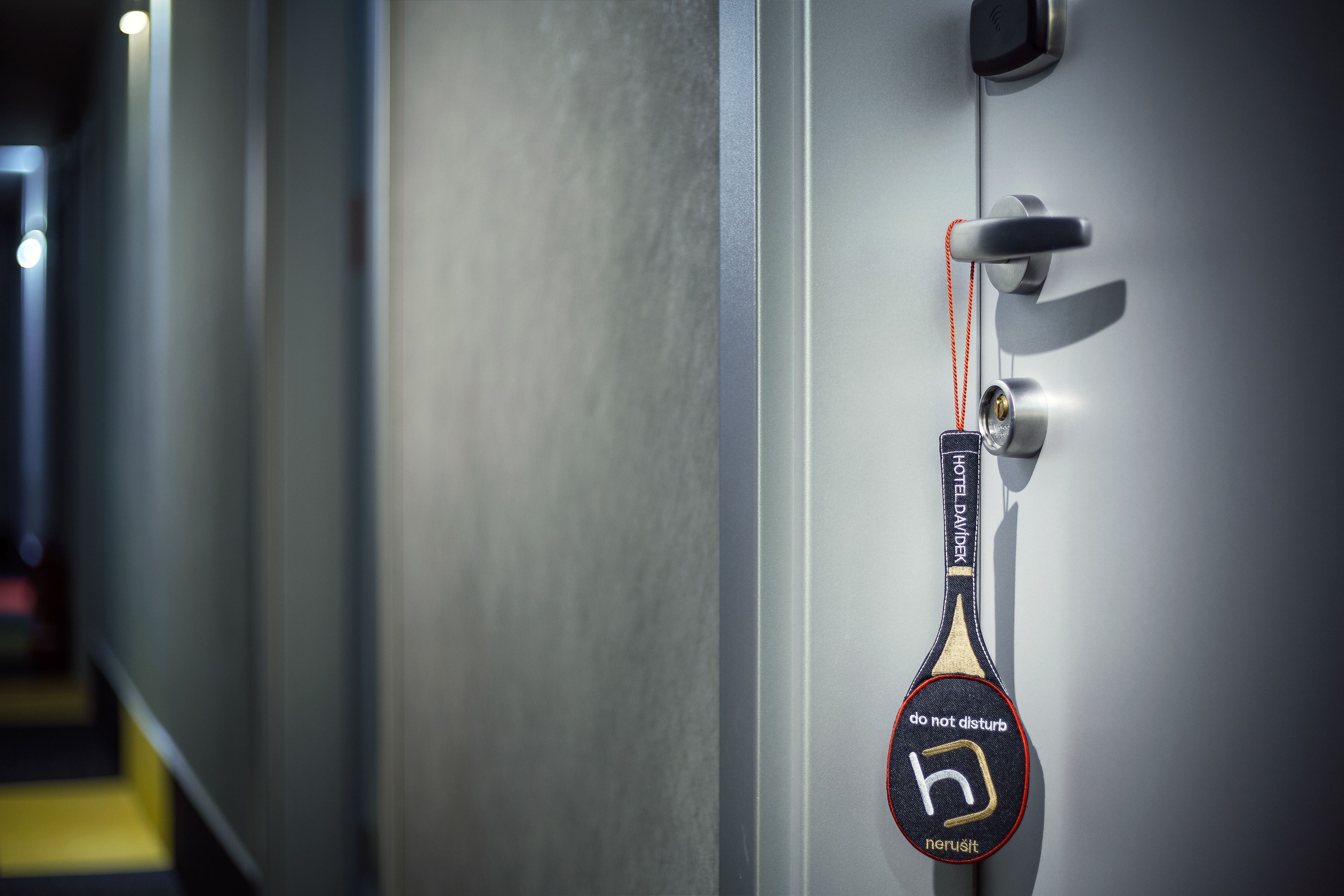 A hotel door with a keycard reader and a 'do not disturb' sign.