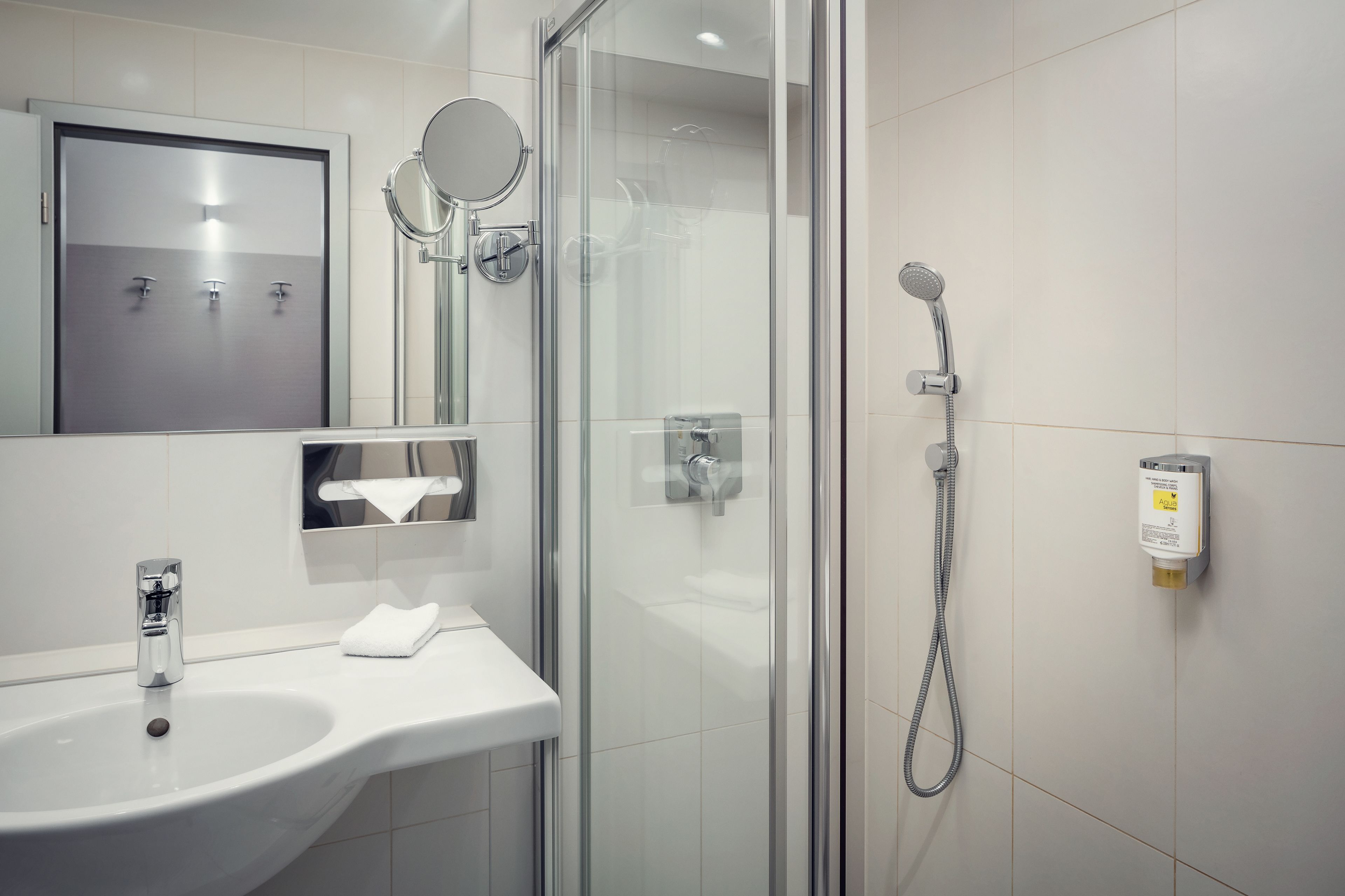 Ein modernes Badezimmer mit Duschkabine aus Glas, Waschbecken mit Spiegel und Handtuchhalter.