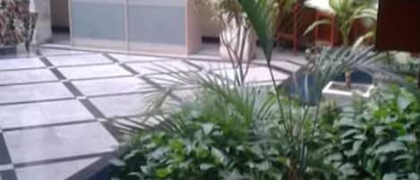 Un patio con suelo de baldosas, plantas en macetas y una zona de estar.