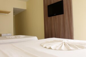 Hotellihuone, jossa on kaksi sänkyä, seinälle asennettu taulutelevisio ja puupaneelilla viimeistelty sisustus.