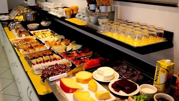 Een buffet met diverse gerechten, waaronder gebak, fruit en kazen.