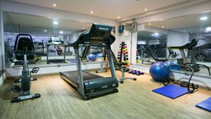 Een fitnessruimte met loopbanden, trainingsballen en een spiegelwand.