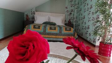 Un dormitorio con una cama, una planta en maceta y una flor roja.