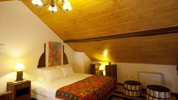 Un dormitorio acogedor con techo de madera, una cama con manta colorida, dos lámparas de noche y un radiador.
