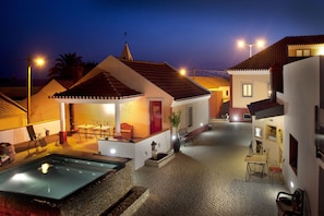 A courtyard with a pool, outdoor seating, and a red door.