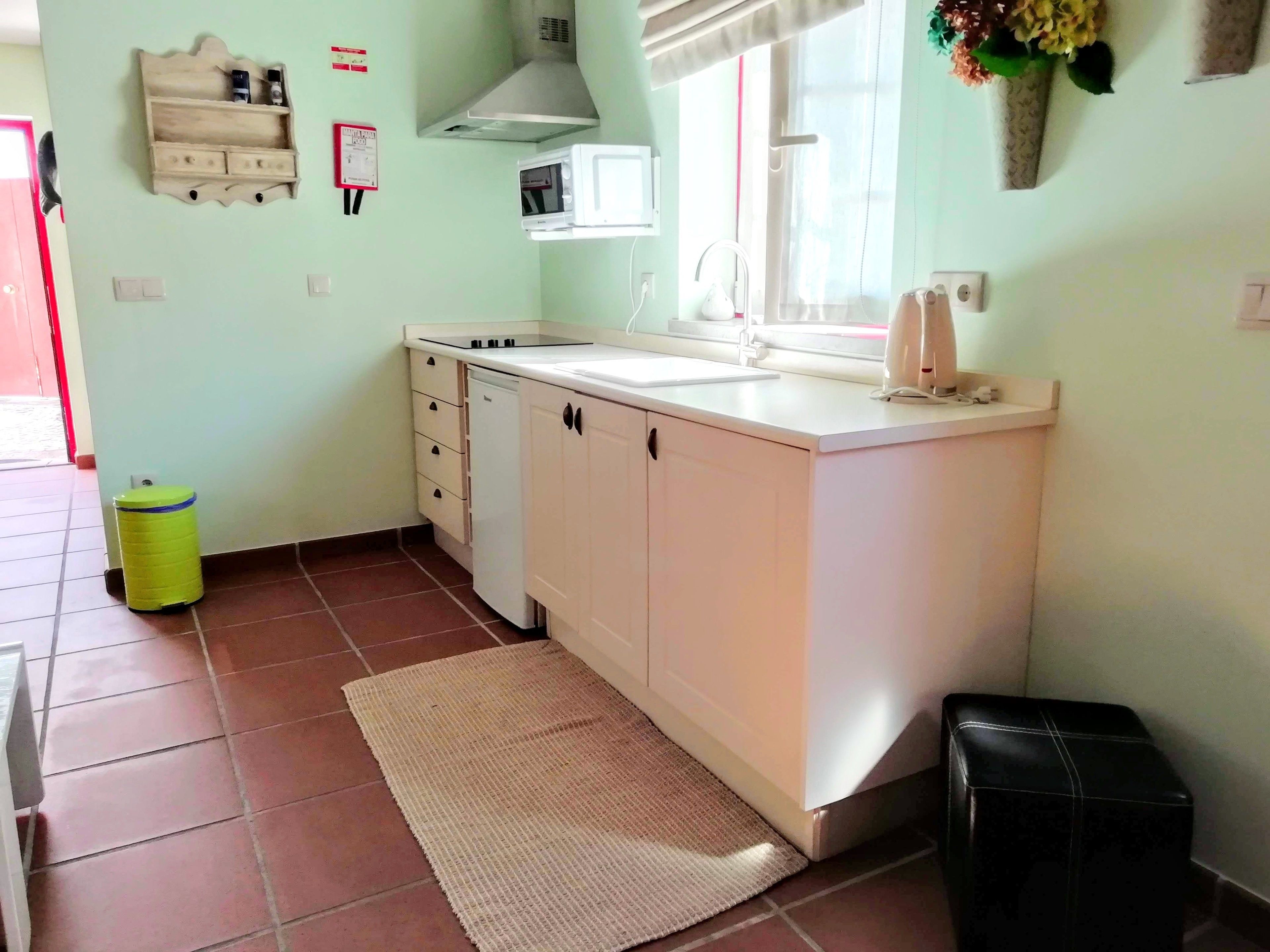 A compact kitchen with white cabinets, a built-in microwave, and a sink.