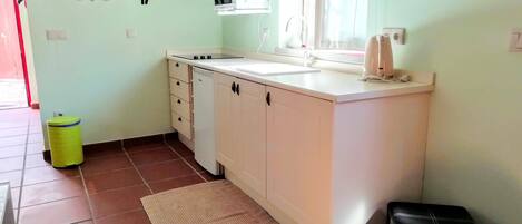 A compact kitchen with white cabinets, a built-in microwave, and a sink.