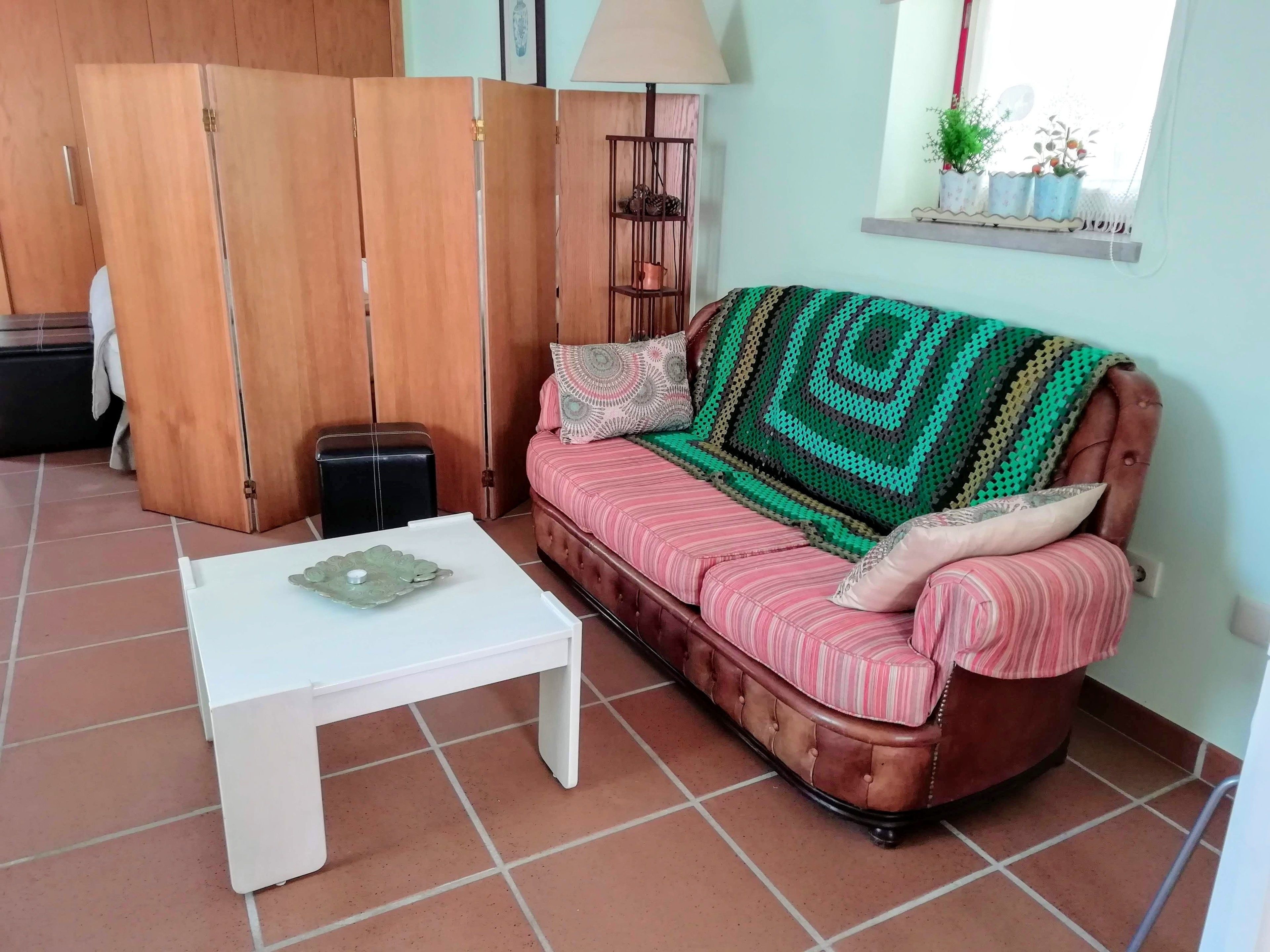 A living room with a brown sofa, a white coffee table, and a wooden wardrobe.